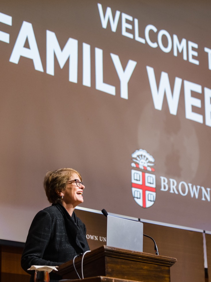 Brown University President Christina H. Paxson in front of a large screen that reads "Welcome to Family Weekend"
